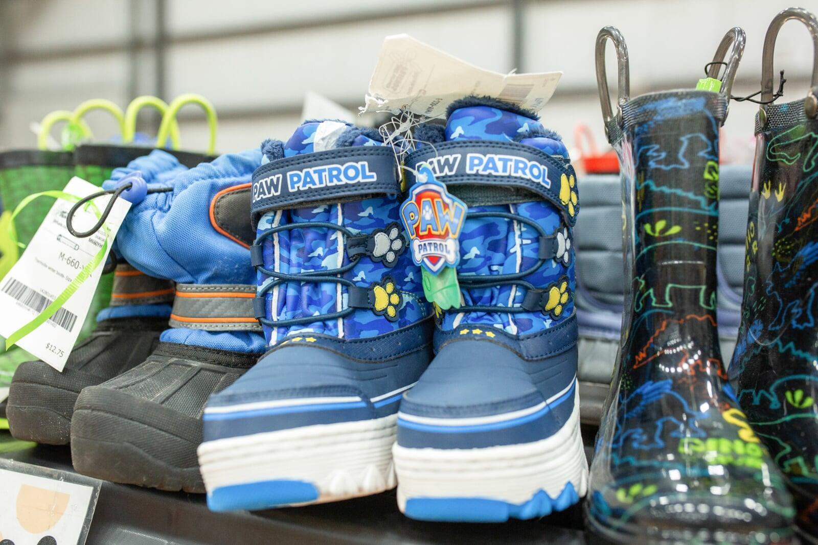A mom and dad shopping at the JBF sale. Mom is holding a purple JBF shopping bag and dad carries his daughter in a front-pack carrier.